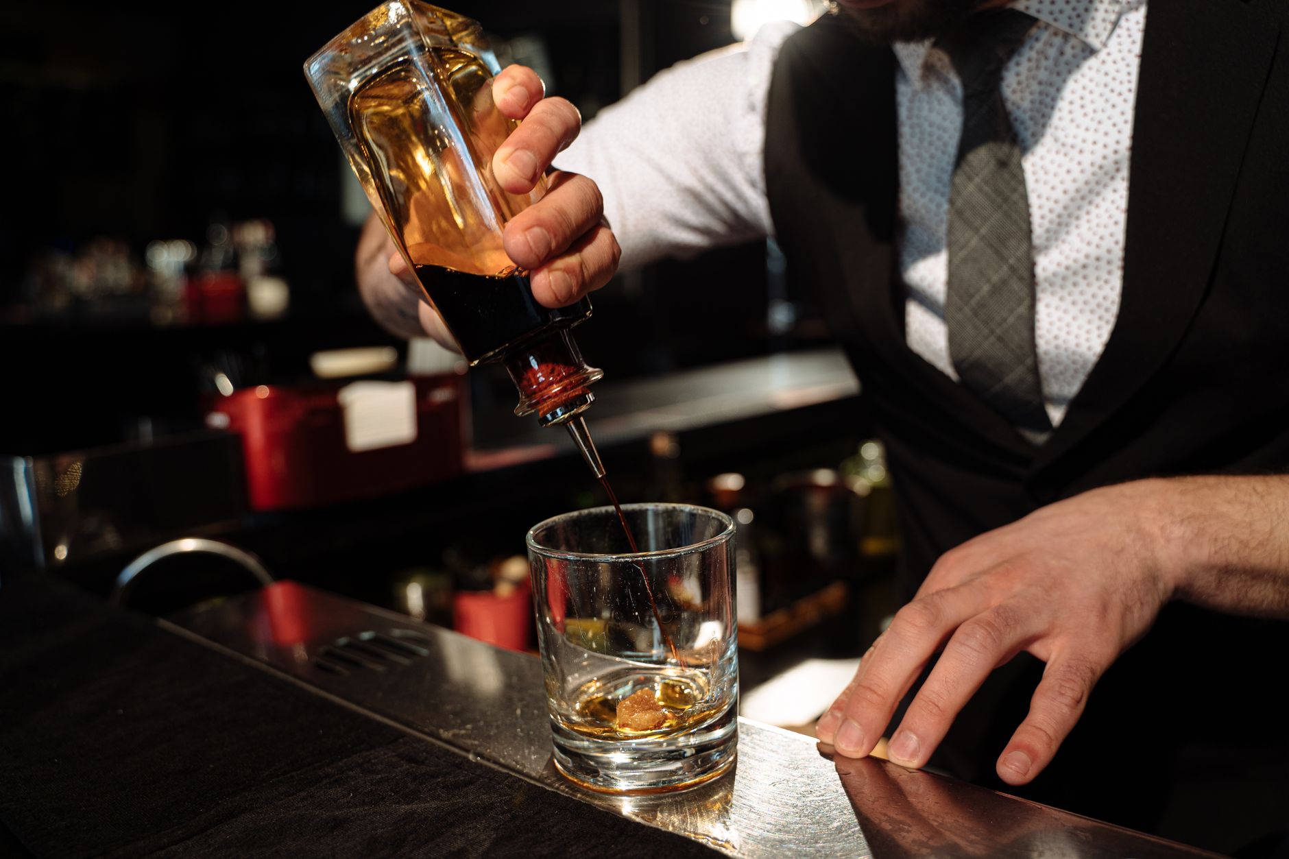 Barman nalewa whisky do szklanki na barowym blacie