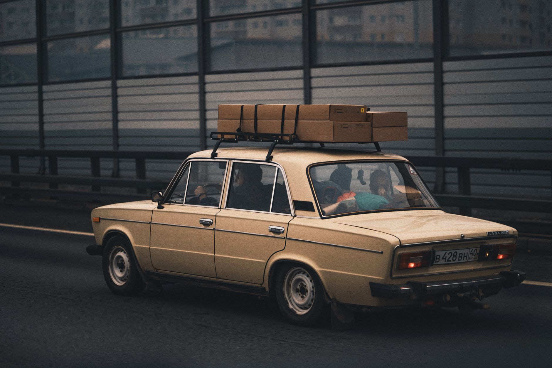 Beżowe Volvo jedzie autostradą z bagażem na tle miasta