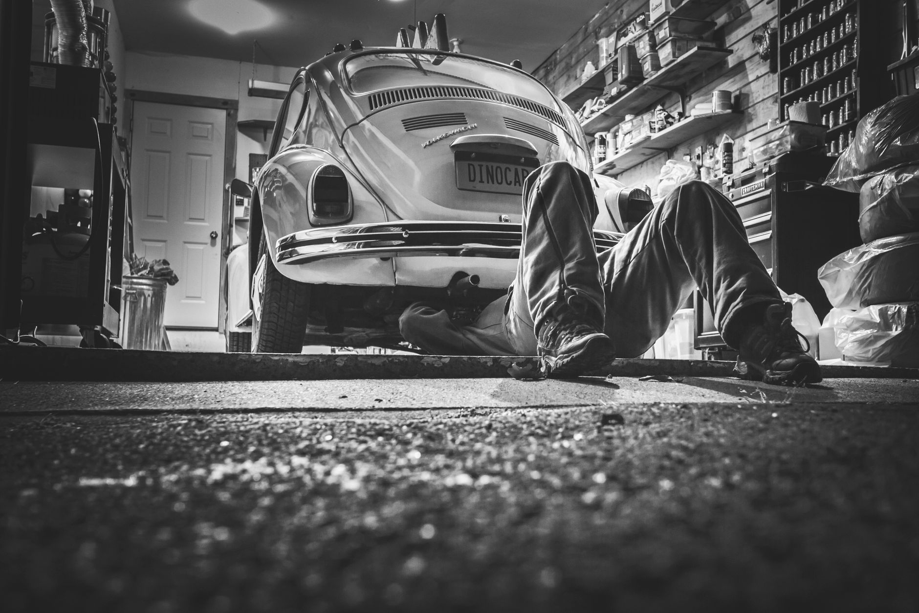 Mechanik pod klasycznym Volkswagenem Garbusem w zabytkowym garażu
