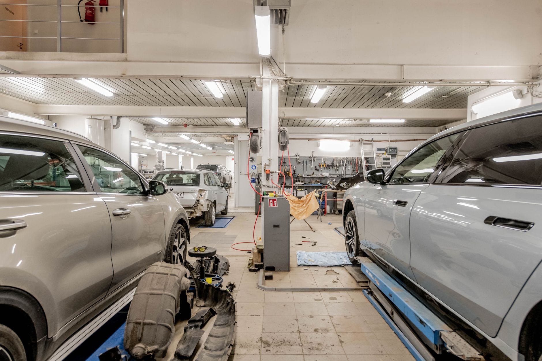 Geely po stłuczce: jak dobrać części, gdzie szukać elementów i ile trwa naprawa Wnętrze warsztatu samochodowego z autami w trakcie naprawy